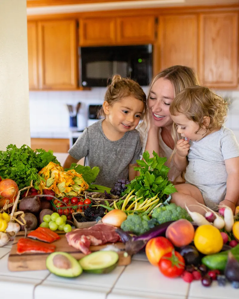 Clare Ramirez with her children at the kitchen counter surrounded by whole ancestral foods