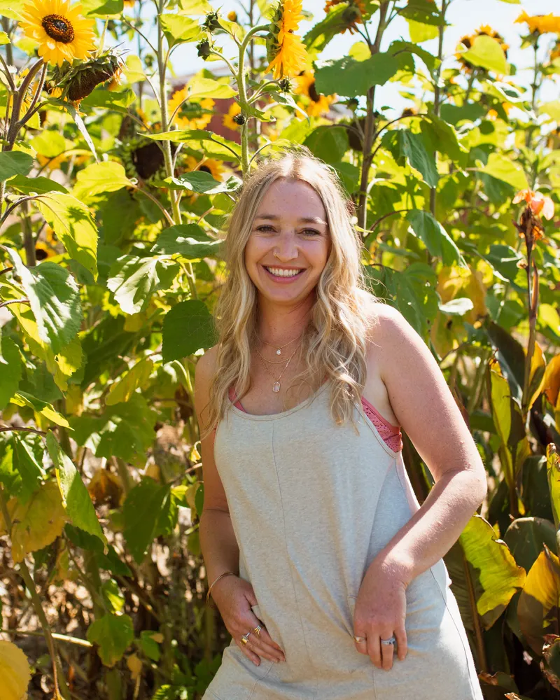 Clare Ramirez outdoors in the California sunshine surrounded by sunflowers