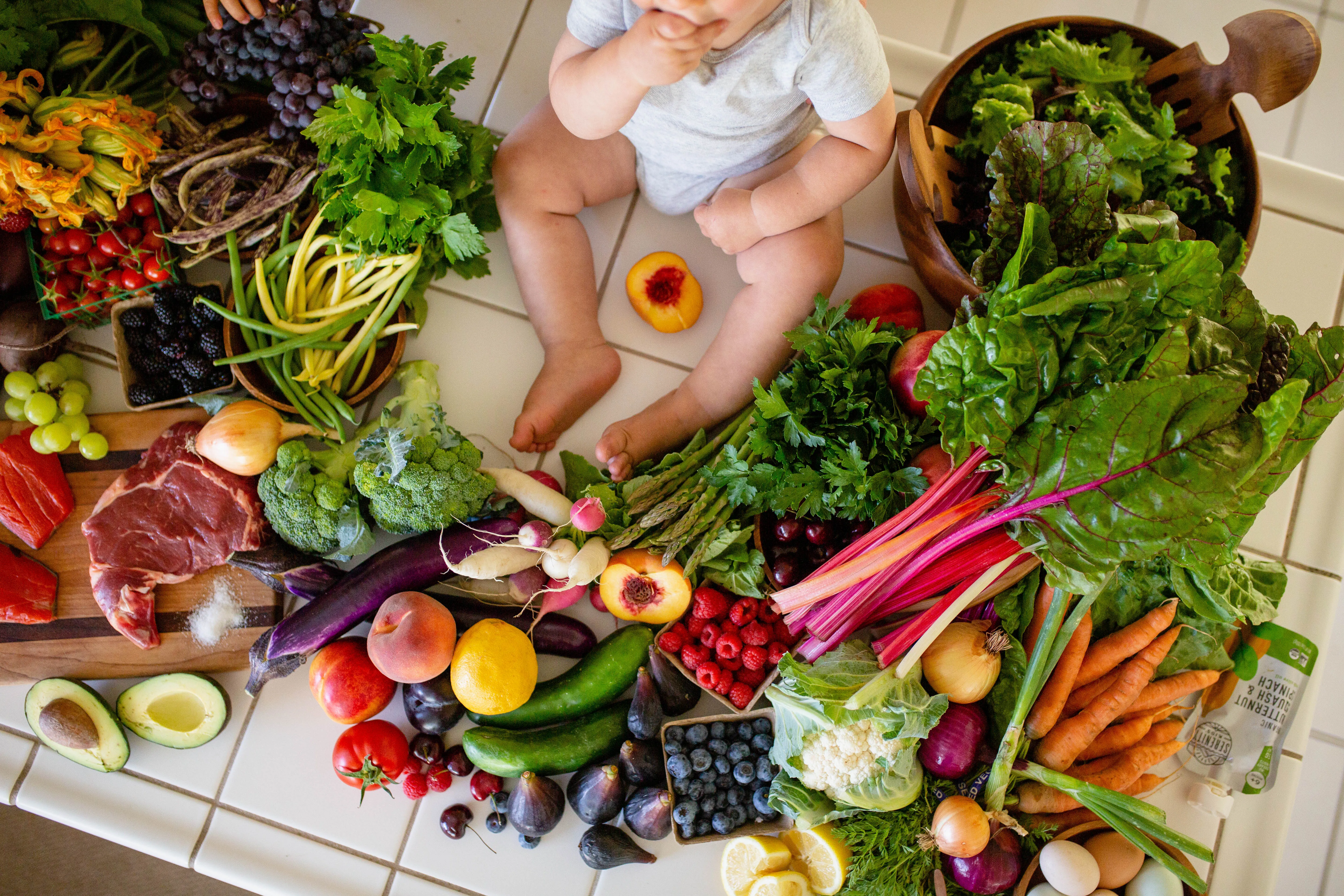 Baby on kitchen counter exploring fresh fruit and nourishing ancestral foods
