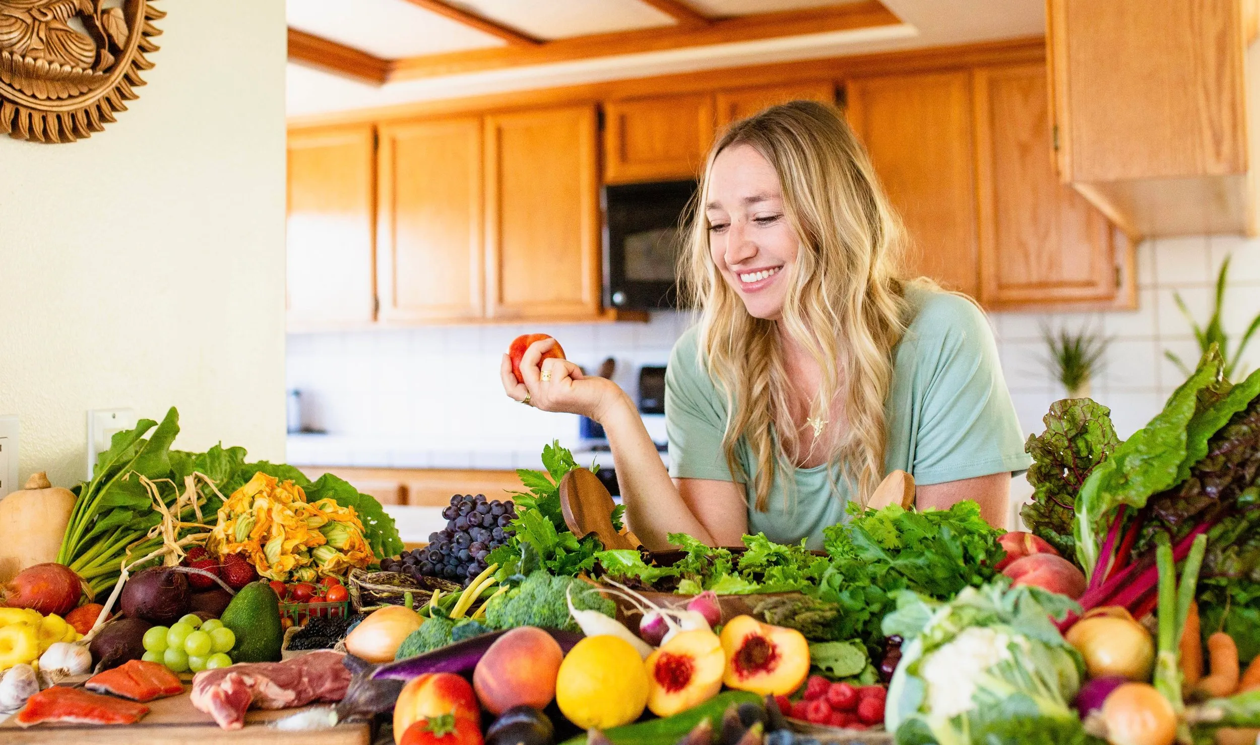 Clare Ramirez smiling in her sunlit kitchen surrounded by fresh produce