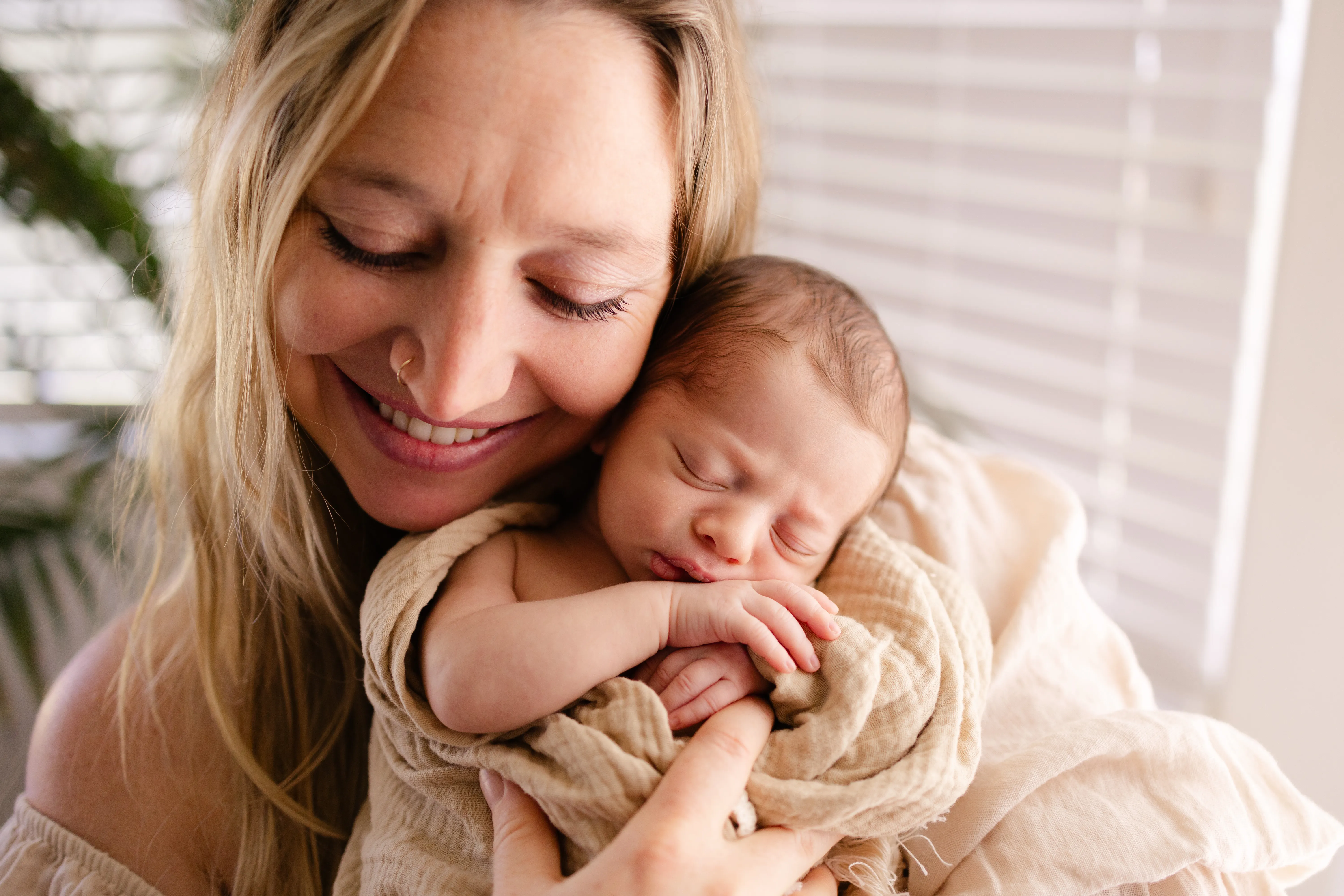 Clare Ramirez tenderly cradling her sleeping newborn on chest during postpartum recovery